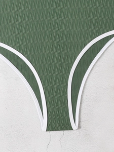 Close-up of deep green wavy textured swimsuit fabric with white contrast piping details