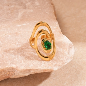 Macro shot of a gold spiral ring with an oval green zircon gemstone on a stone