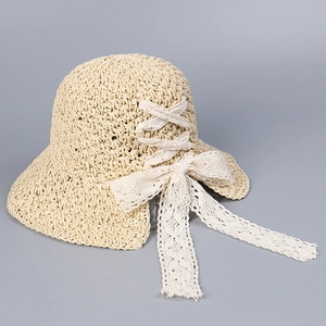 Close-up of the beige straw sun hat featuring intricate weave and a white lace bow detail