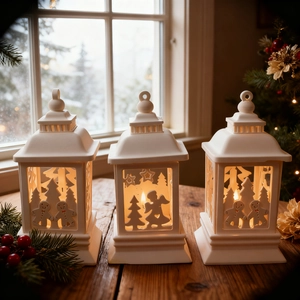 Three-piece set of white Christmas lanterns with snowflake and angel cutouts on wood table