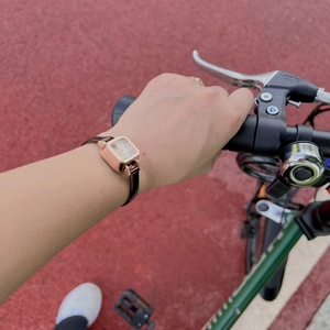 Minimalist square rose gold watch with dark leather strap shown in outdoor setting