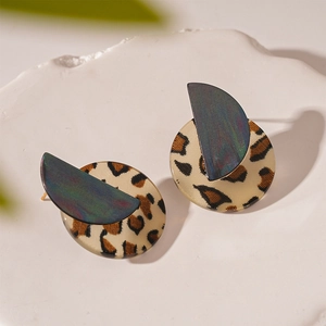 Detailed close-up of leopard print acrylic earrings with iridescent oil slick finish