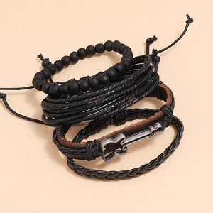 Close-up of stacked leather bracelets set featuring a guitar charm and braided bands