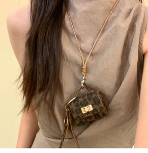 Detail of leopard print leather mini bag pendant necklace worn with brown ribbed top