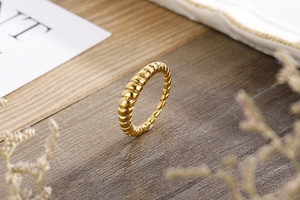Detailed close-up of a gold-plated croissant ring with spiral texture on a wooden desk