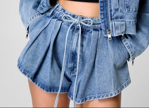 Detailed view of high-waisted pleated denim shorts with drawstring and washed texture