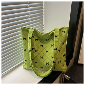 Dettaglio ravvicinato della borsa tote in velluto verde con stampa di fiocchi e rombi