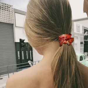 Detail of vibrant orange Halloween scrunchie with dark pattern tied on a low ponytail