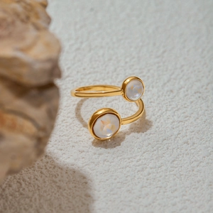Minimalist gold titanium steel open ring with two white opal stones on natural rock