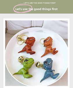 Detailed view of colorful cartoon T-Rex dinosaur keychains with bells in a 4-pack set