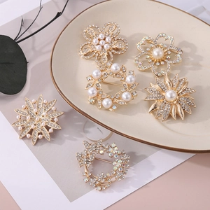 Ensemble de broches fleurs dorées avec perles et strass sur plateau en céramique