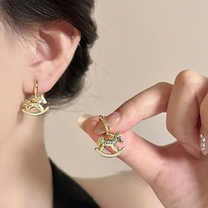 Close-up of model wearing 18k gold plated rocking horse earrings with retro metal finish