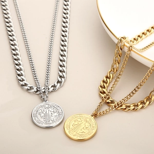 Detailed close-up of gold and silver layered necklaces with Saint Benedict medals