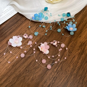 Detail of floral fabric tassel earrings with pink and blue beads on a wood background