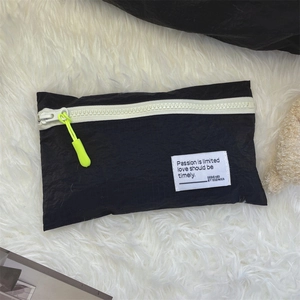 Detail of black nylon travel organizer bag with white zipper and neon lime puller tab