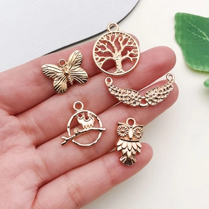 Rose gold DIY charms set with butterfly, tree of life, owl and wings on a hand