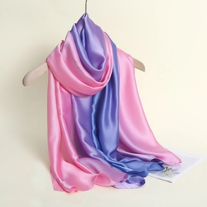 Detailansicht eines Seidenschals mit rosa lila blauem Farbverlauf am Holzkleiderbügel