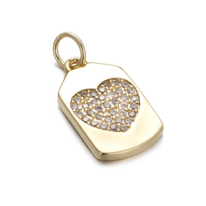 Detail shot of a golden rectangular pendant featuring a heart-shaped zircon inlay