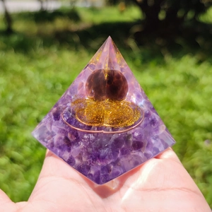 Detailed close-up of Orgone pyramid with amethyst crystals and golden metal coil