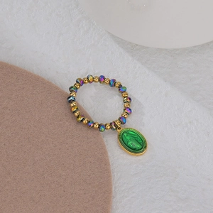 Elastic beaded ring featuring gold and green beads with a Virgin Mary religious pendant