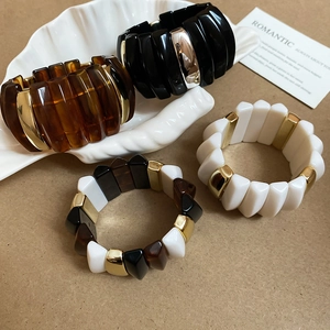 Detail of acrylic rectangular resin bangles in amber, black and white on shell tray