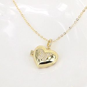 Detailed view of an openable gold heart locket necklace with a diamond butterfly pattern