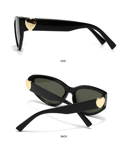 Detail view of black sunglasses with golden heart-shaped metal accents on the temple