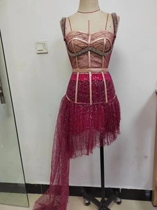 Detail of rose red sequined dress with corset bodice and beaded mesh asymmetrical hem