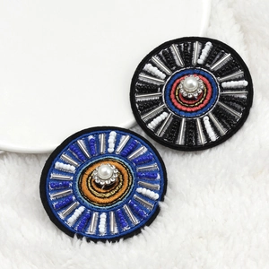 Detailed view of handmade Evil Eye brooches with embroidery, pearls, and crystals