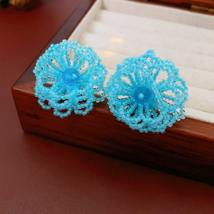 Detail of hand-woven light blue crystal flower studs with deep blue center bead