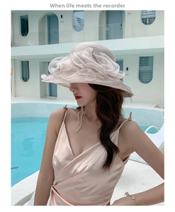 Detail of pink organza floral sun hat with a wide brim against a blue pool background