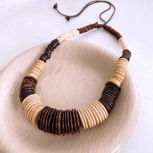 Macro shot of bohemian wooden and coconut shell bead necklace in a ceramic bowl
