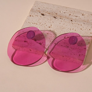 Detail of translucent dark pink oval resin earrings on a textured travertine stone