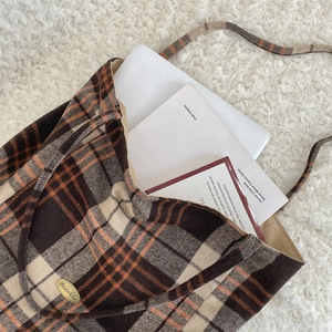 Detail showing a 15-inch laptop inside a plaid wool tote bag for commute capacity