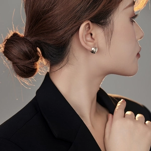 Close-up of model wearing silver heart-shaped hoop earrings with a polished metal finish