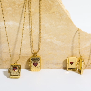 Macro detail of three golden photo locket necklaces with a red heart zircon and sunburst texture