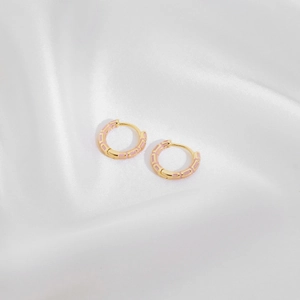 Elegant gold bamboo-joint hoop earrings with pink enamel inlay on white silk fabric