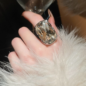 Detailed close-up of large oval-cut crystal ring with silver four-prong setting on hand