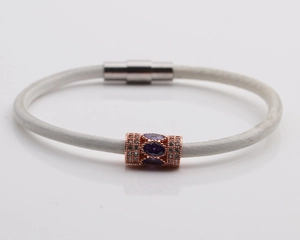 Detail of white leather cord bracelet with rose gold bead, purple stone and magnetic clasp
