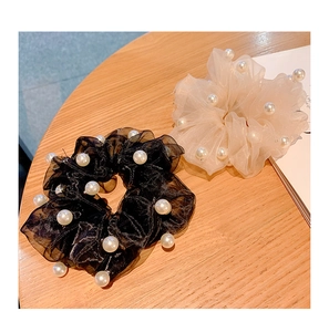 Detail of black and beige organza hair scrunchies with elegant pearls on a wooden table