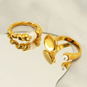Fashionable 18K gold plated stainless steel rings with elegant white pearls on a mirror