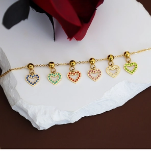 Detailed shot of golden bracelet featuring heart pendants with colorful rhinestones