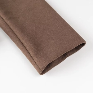 Détail de la manche du manteau en laine marron montrant le tissu et les coutures propres