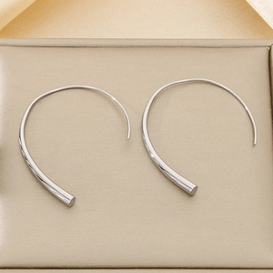 Macro shot of minimalist silver-tone titanium steel earrings on a champagne velvet box