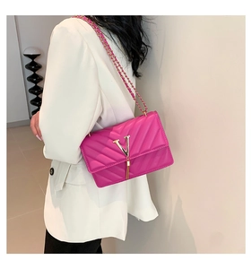 Detail der pinkfarbenen Stepptasche mit goldenem V-Logo und Quaste auf weißem Blazer