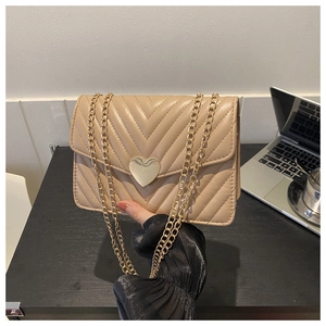 Dettaglio borsa a tracolla beige trapuntata a V con chiusura a cuore dorata
