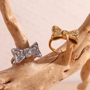 Detail of gold and silver bow rings with micro-inlaid crystals on a rustic branch