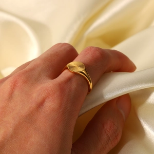 Gros plan d'une bague chevalière soleil plaquée or 18 carats sur fond de soie douce