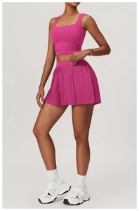 Detail of hot pink square neck yoga top and pleated tennis skirt set on model