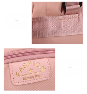 Detail of pink mummy bag showing reinforced stitching and gold-toned fashion logo